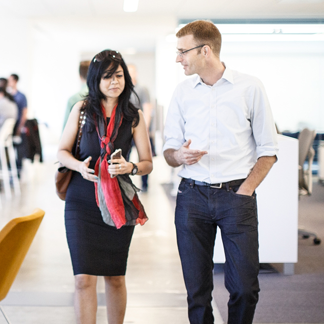 Man and woman walking together through a building and talking. 